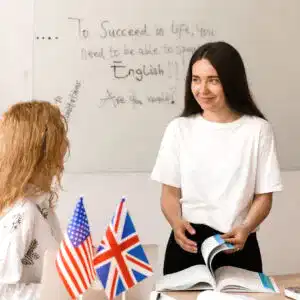 Teacher of english asks student in white class. 2 girls student answers to teacher. Working in group. Study english and british language.